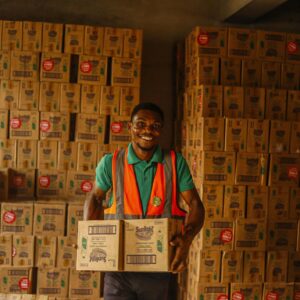 Smiling Man Working in a Warehouse Holding Boxes